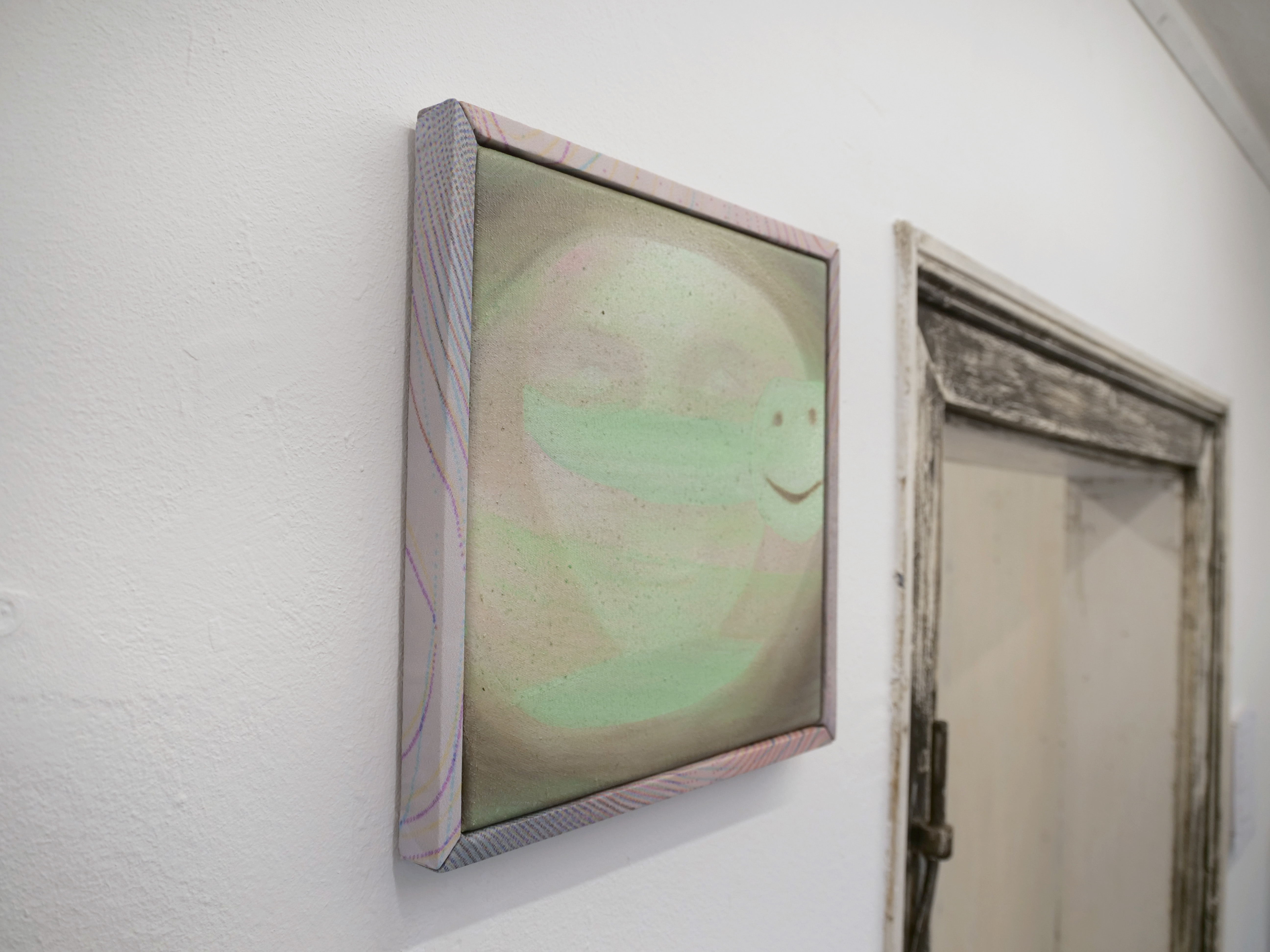 Oil painting by Tejzt: 'Digital Persona Autophagy'—A smiling, ghostly figure emerges from the canvas, its presence flickering between existence and dissolution. The painting captures the eerie disconnect between one's real self and the digital persona—an entity fed and shaped online, yet increasingly alien to its creator.