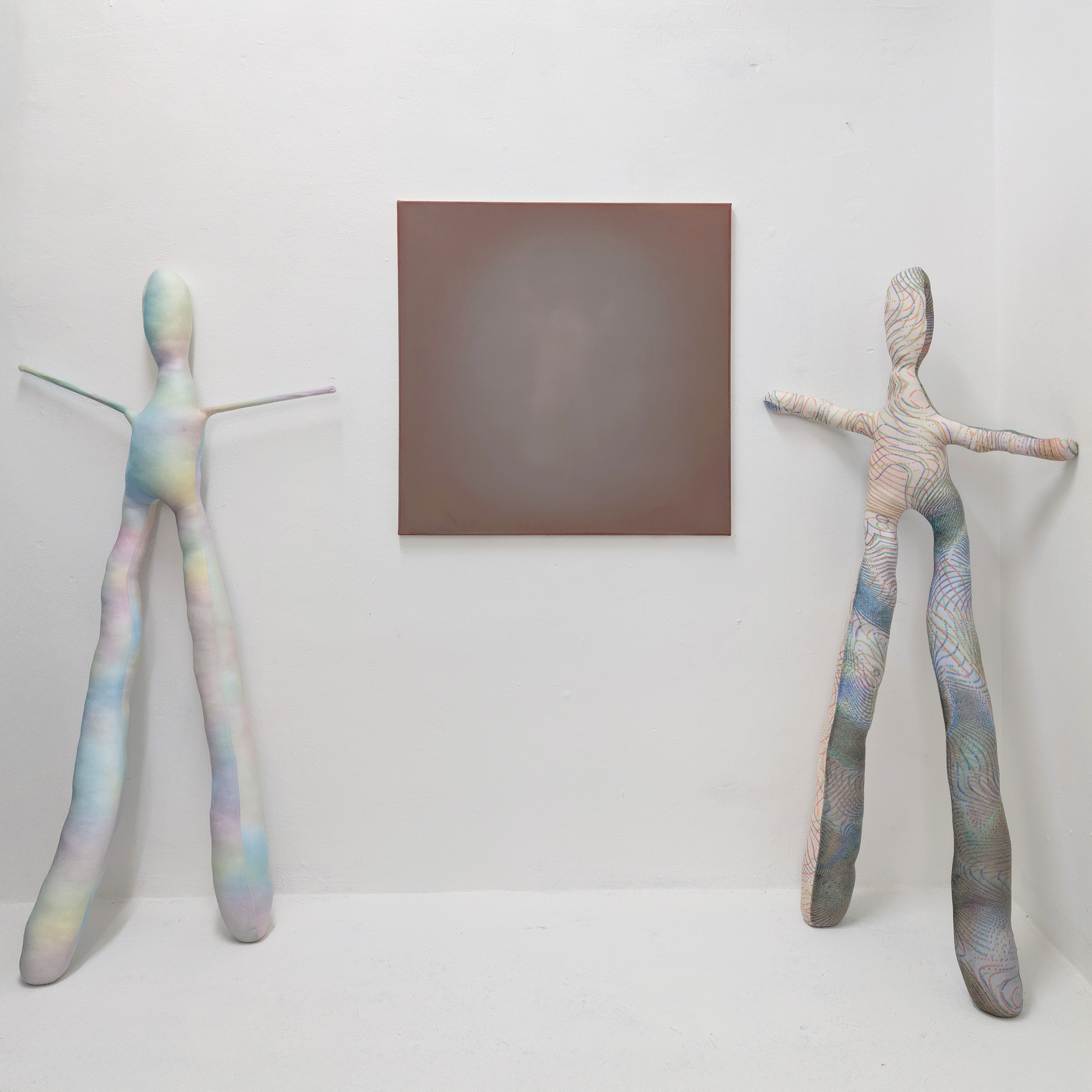 Oil painting by Tejzt: 'Vorfreude aufs Jenseits'—a radiant, luminous figure emerges from the canvas, barely perceptible yet intensely present. The work evokes a hagiographic vision, reminiscent of depictions of saints or ascended beings. It explores the **light body phenomenon**, where perception dissolves into a heightened state of awareness. The appearance is both ethereal and monumental, blurring the threshold between **matter and light, body and vision, self and beyond**. Two fabric sculptures flank the piece, serving as a scale reference, reinforcing the sensation of encountering an otherworldly presence.