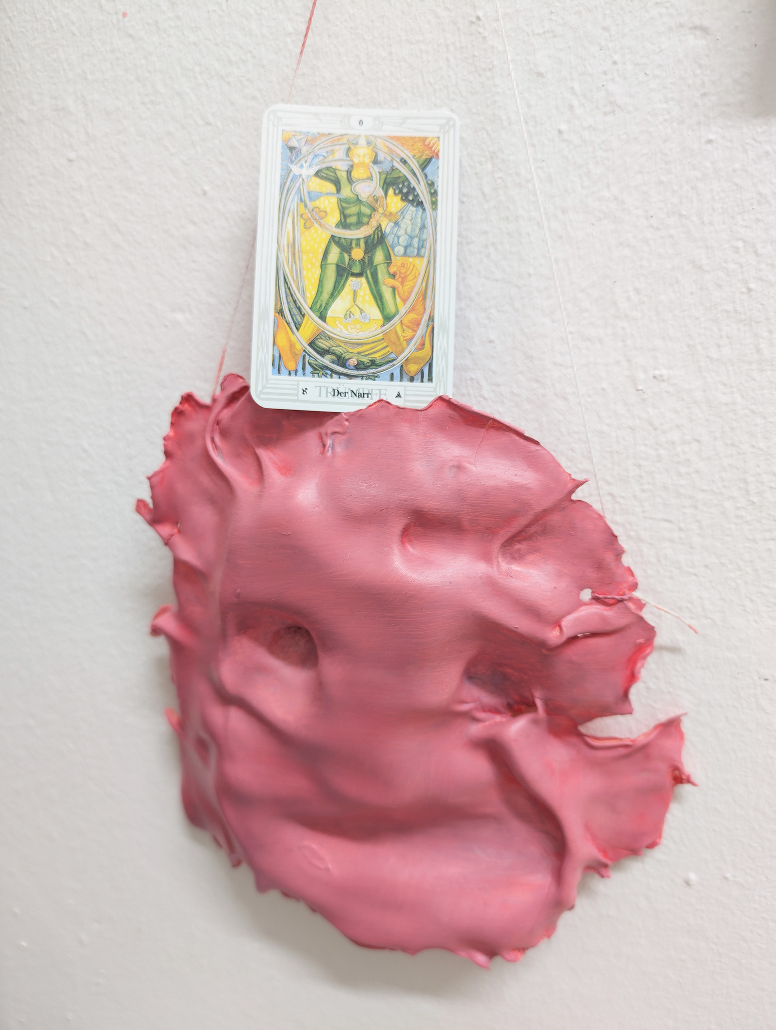 Tejzt — tarot card 'Der Narr' above a pink wax / paint mask relief, wall detail (2025)