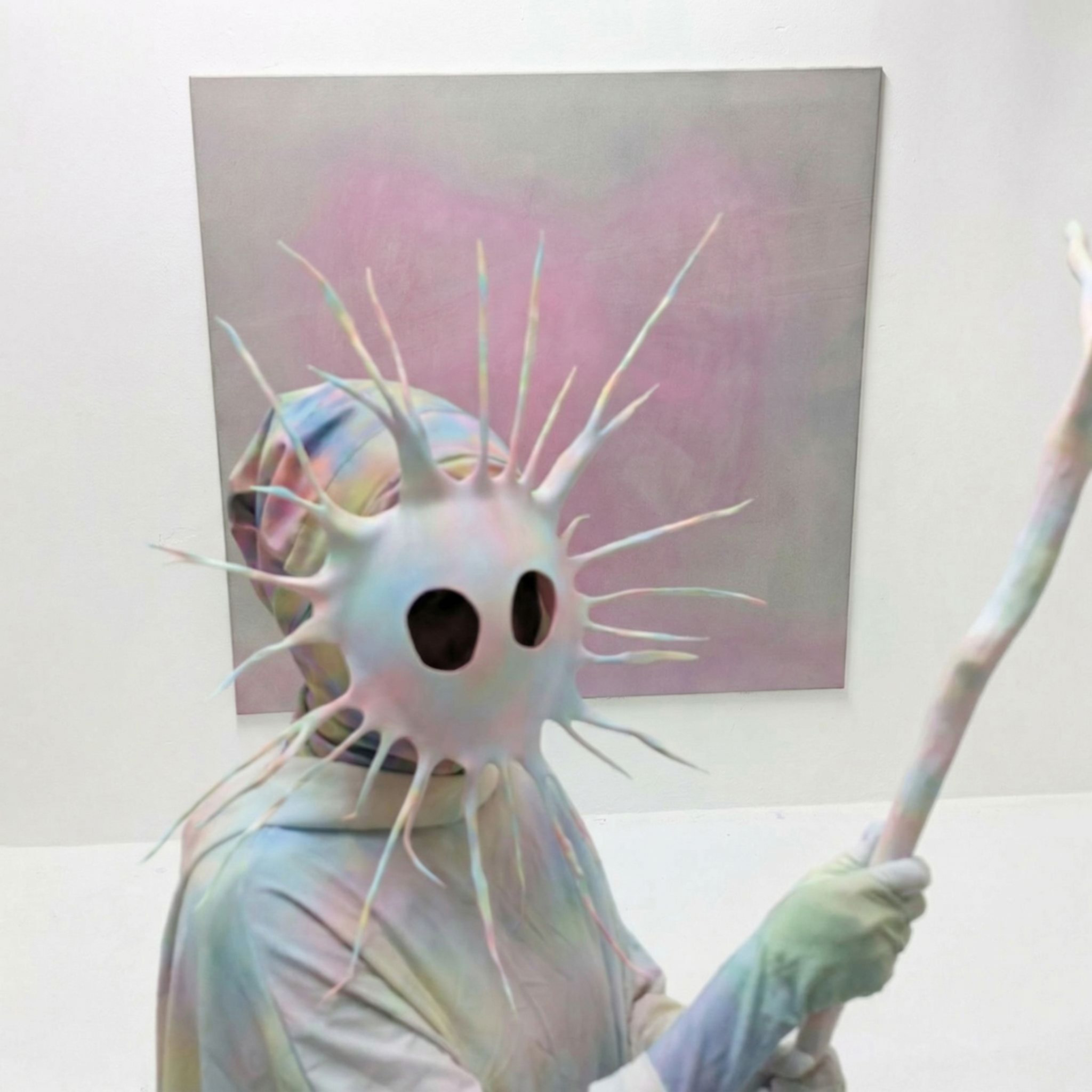 Tejzt — Efee figure with spiked mask in front of a soft gradient painting, holding a staff, studio image (2026)